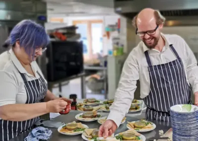 Two people in aprons ready to serve a meal