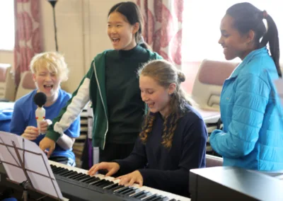 Teenage girls singing around a keyboard