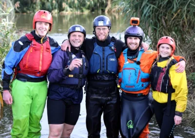 Group of people in water sport kit next to a river Gap team