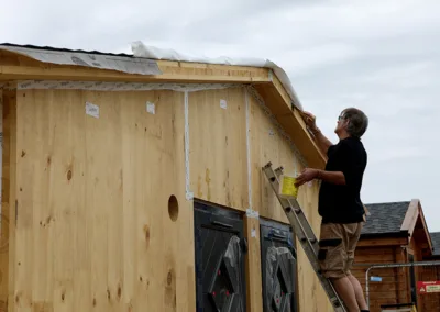 Man on a ladder leaning against timber building