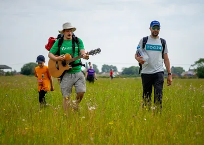 Leader playing the guitar walking across a wildflower meadow