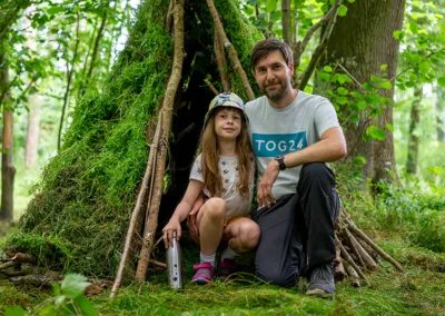 Father and daughter posing outside a hideout in the woods