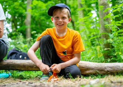 young boy in woodland setting smiling at the camera